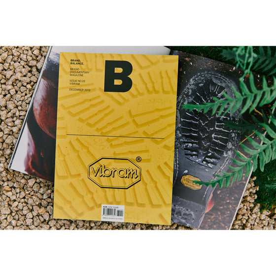 Magazine B - Issue 22 Vibram. A photo of the magazine resting on a surface outside, with an open page of the magazine partially visible in the background.