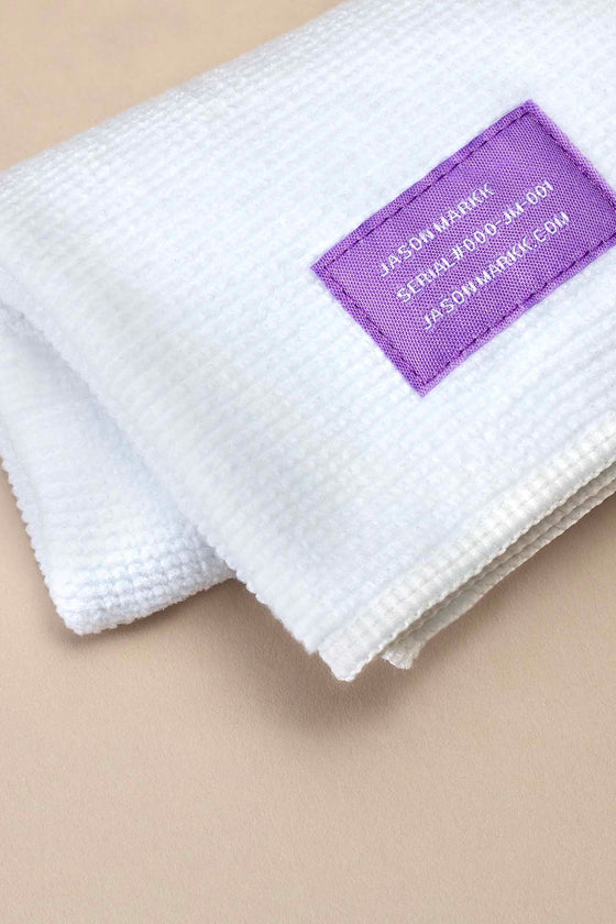 Jason Markk Premium Microfiber Towel. Close-up of the towel showing the logo, highlighting its fine microfiber texture that captures dirt and dust for a lint-free finish.