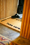 Jason Markk Shoes Off Welcome Mat. A close-up of shoes being wiped on the mat, showing how it effectively removes dirt and debris before entering the home.